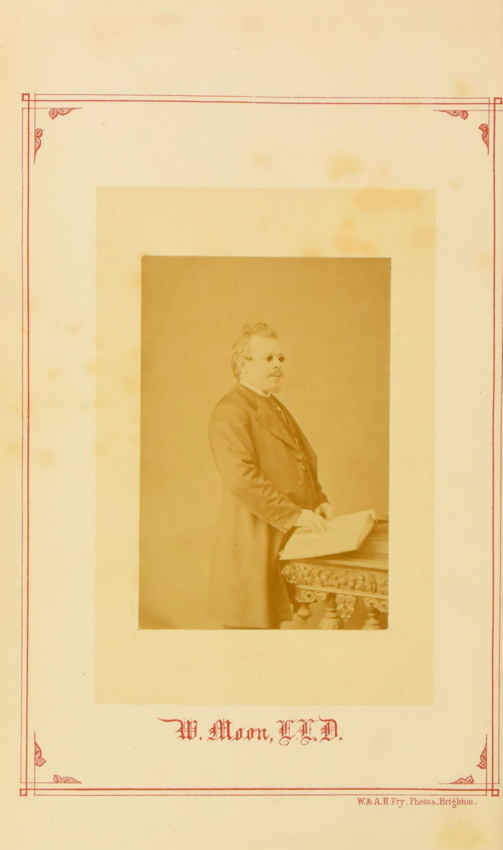 A photograph of William Moon in middle age, standing at a table with one hand resting on an open embossed book. Below it his signature, "W. Moon, LL.D."